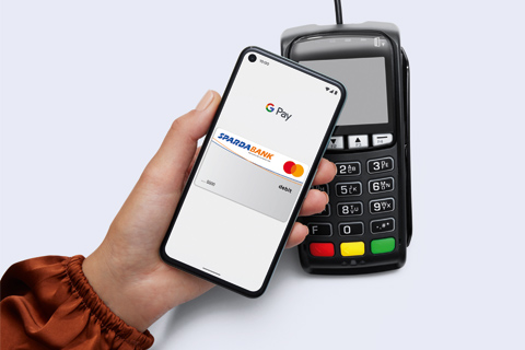 Eine Hand hält ein Smartphone mit Google Pay am Bildschirm zum Bezahlen hin.